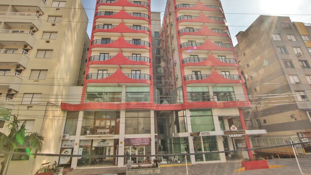 A multi-story hotel with balconies, a ground-level restaurant, and a visible sign for a hotel named "Hotel Encantos."