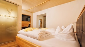 A hotel room with a bed, wooden headboard, and a wall with a deer logo. - Hotel zum Hirschen in Lam (Lam)