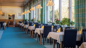 A restaurant with a long table layout, large windows, and hanging pendant lights. - Hotel zum Hirschen in Lam (Lam)