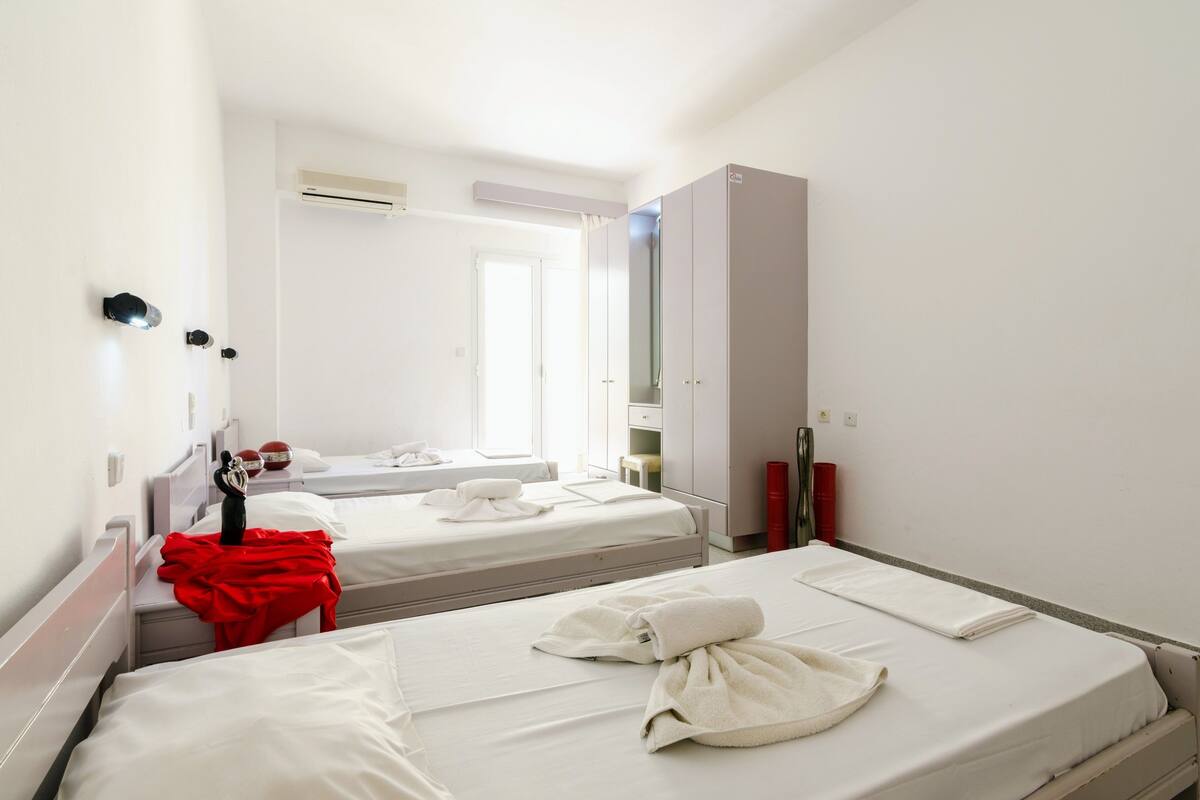 Quarto de hotel com duas camas, um guarda-roupa, um espelho e uma janela.