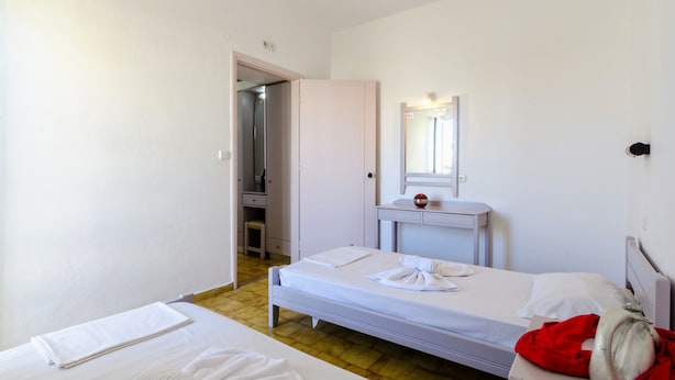 A hotel room with a single bed, a small bedside table, a mirror, and a wardrobe. - Village Oasis - Annex (Hersonissos)