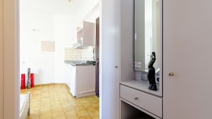 A narrow hallway leading to a kitchen with a tiled floor, a white refrigerator, and a sink. - Village Oasis - Annex (Hersonissos)