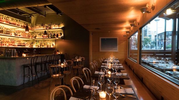 A restaurant with a bar area, wooden interior, and a view through large windows. - The 404 Hotel (Nashville)