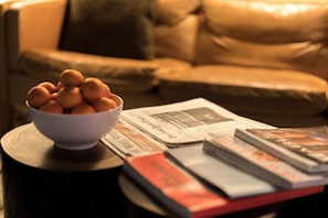 A bowl of oranges on a wooden table with books and newspapers. - The 404 Hotel (Nashville)