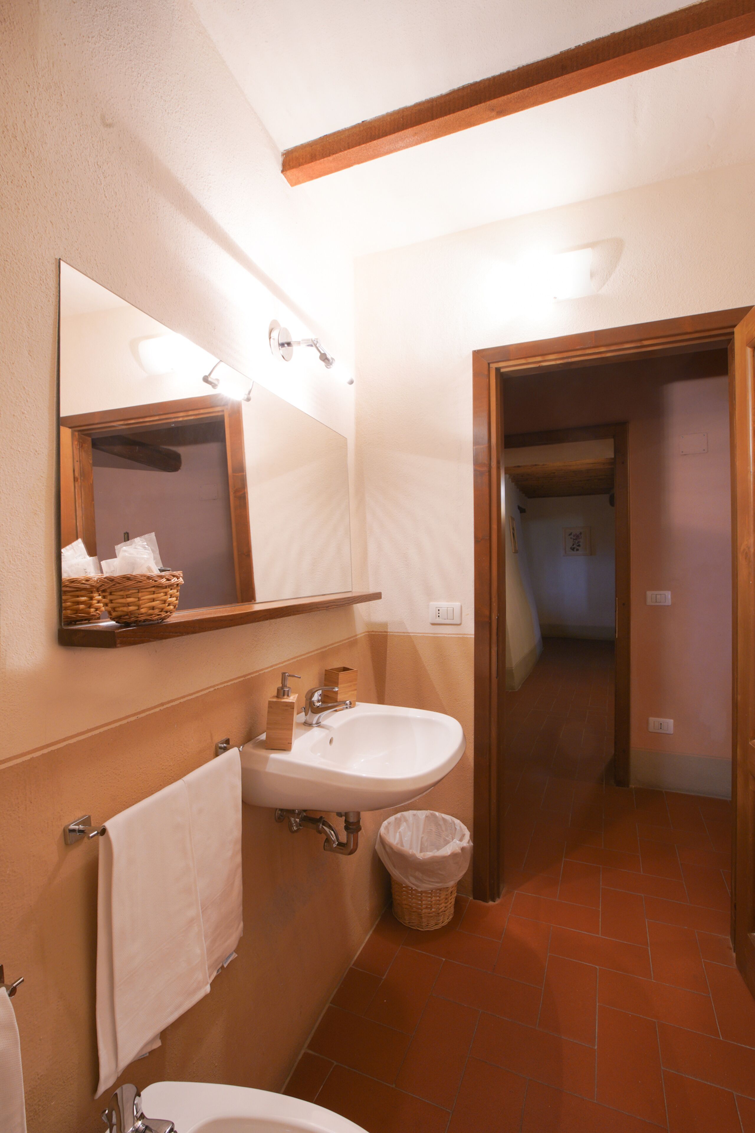 Un bagno con due lavandini, uno specchio e un cesto a parete.