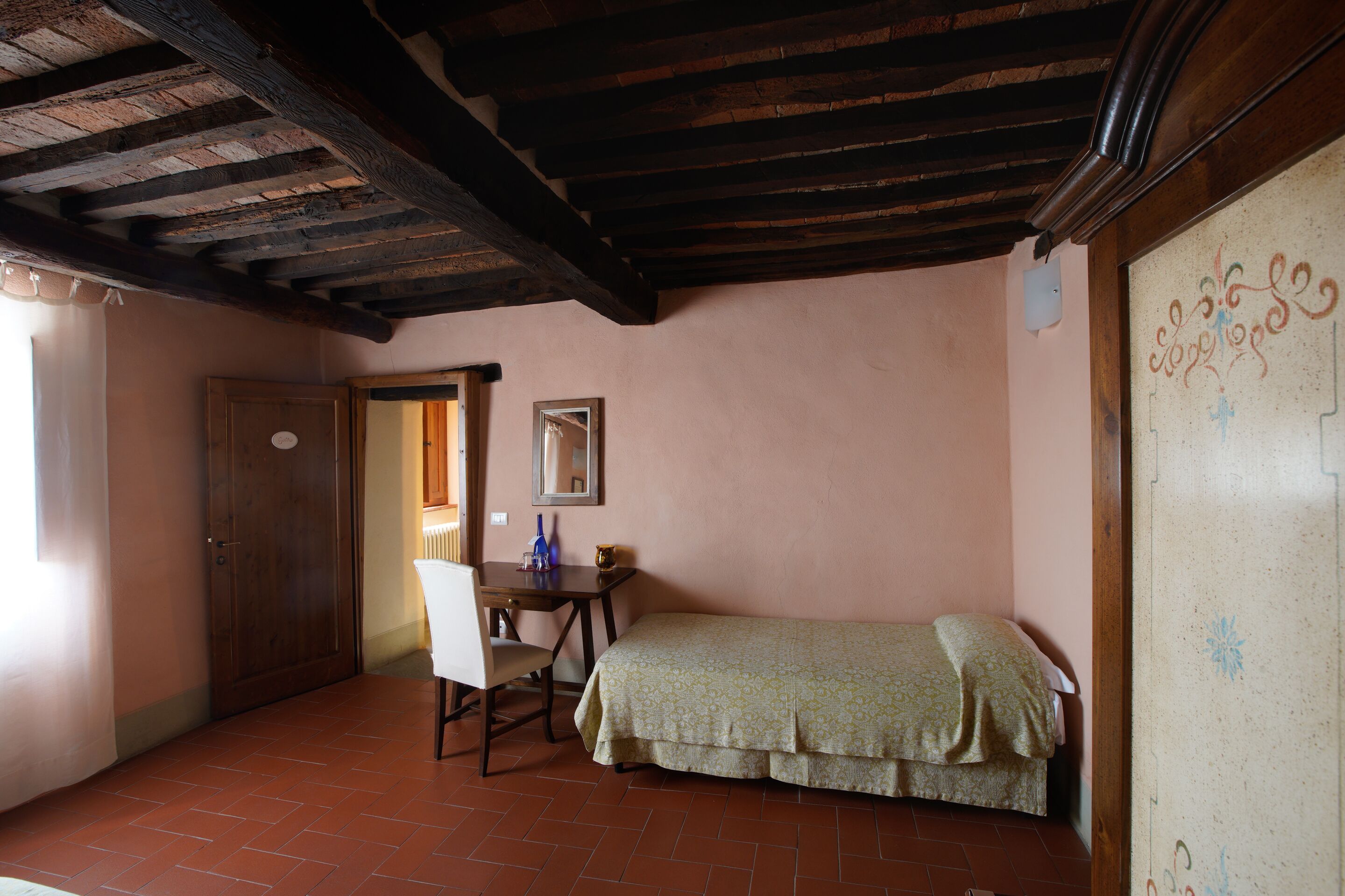 Une pièce avec un lit, un bureau et une chaise. Il y a une porte et une fenêtre.
