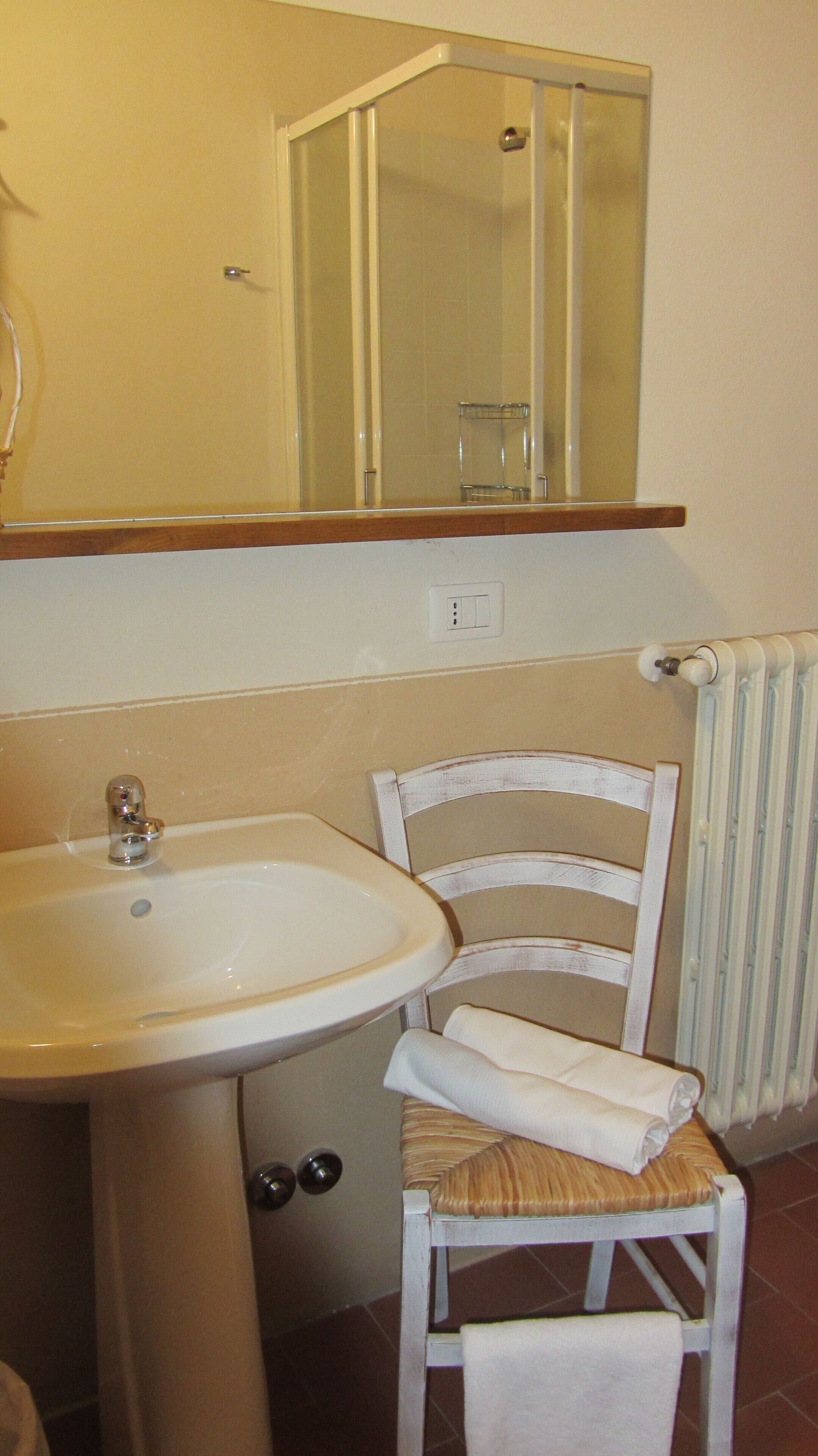 A bathroom with a sink, mirror, and chair.