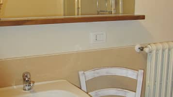 A bathroom with a sink, mirror, and chair.