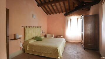 Une chambre à coucher avec un lit, une chaise, une armoire et une fenêtre avec des rideaux.