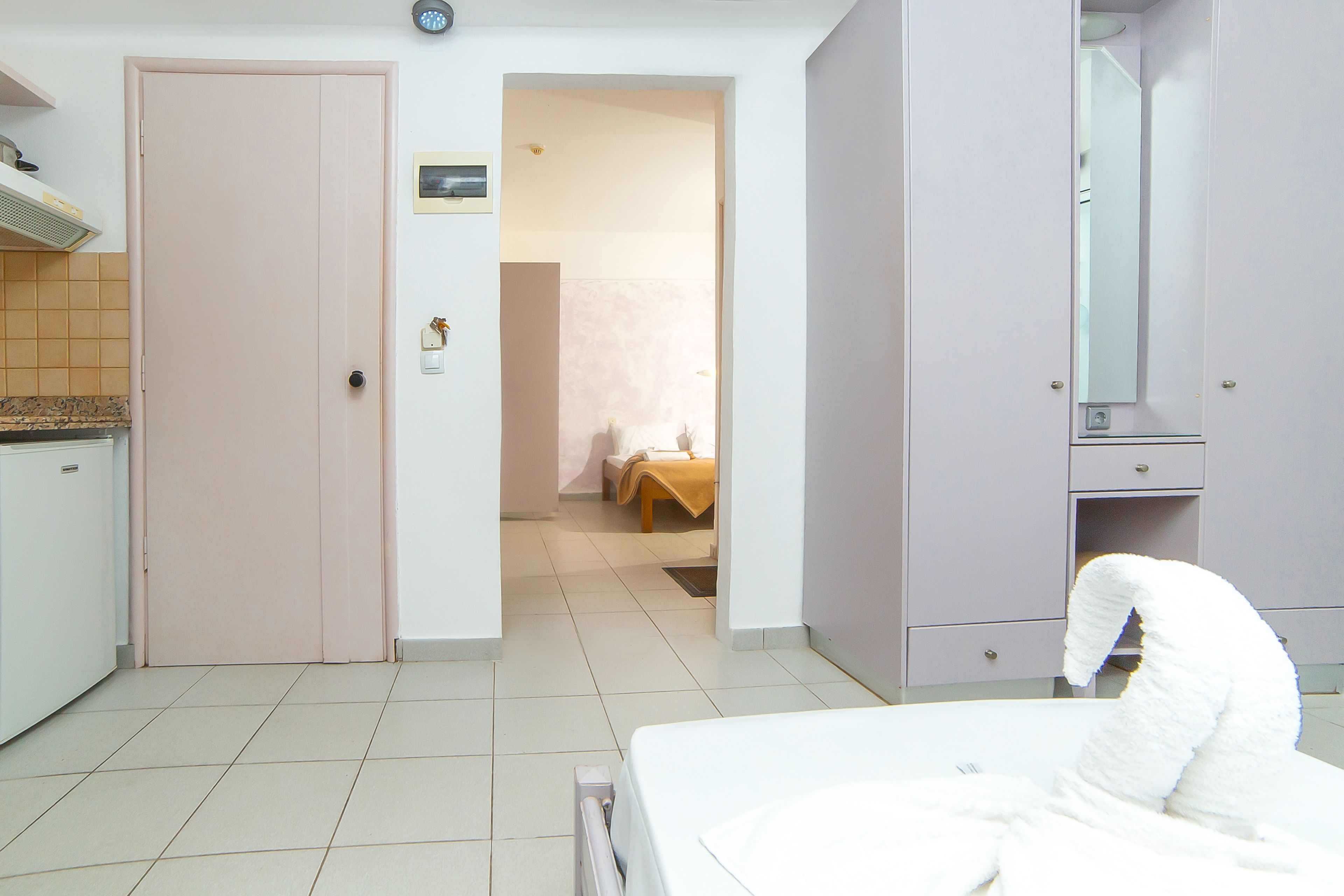 Habitación de hotel con cama, baño con espejo y zona de kitchenette.
