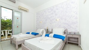 A hotel room with two beds, a glass door leading to an outdoor area, and a marble-patterned wall. - Stonewell (Hersonissos)