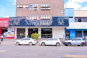 A hotel with a sign that reads 'Nev's Hotel' and a logo with 'NH'. There are three cars parked in front. - Oft Neve's Hotel (Goiania)