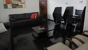 Un espacio de oficina moderno con un sofá de cuero negro, una mesa de centro de cristal y un mostrador de recepción con computadoras.