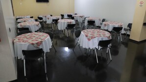 Un salón de conferencias con varias mesas y sillas, un televisor de pantalla plana en la pared y un cartel de prohibición.