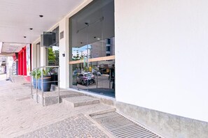 A building entrance with a glass facade, a metal staircase, and a paved walkway. - Oft Neve's Hotel (Goiania)
