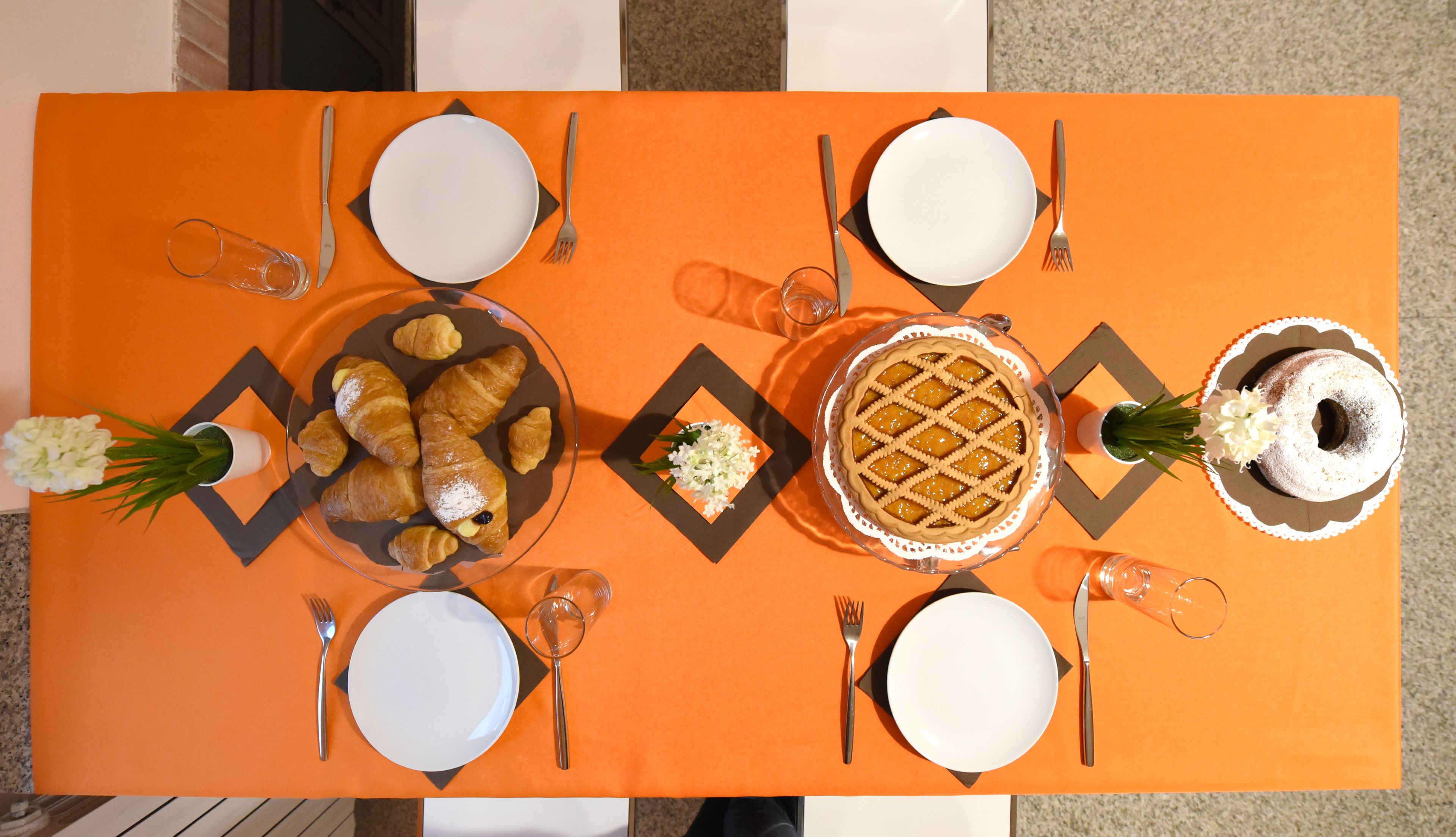 Una mesa servida para una comida con platos, cubiertos y una variedad de postres.