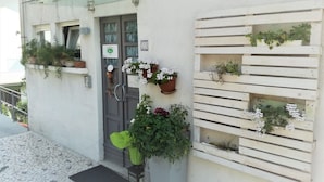 A building with a tiled entrance, a glass door, and multiple flower planters on the exterior walls. - B&B Cappuccini (Schio)