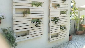 Two vertical wooden planters mounted on a wall, each containing various plants and flowers. - B&B Cappuccini (Schio)