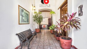 A hallway with a bench, potted plants, and a sign for "Capital O Posada El Nito". - Capital O El Nito Posada (Oaxaca)