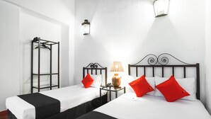 A hotel room with two beds, each with white bedding and black headboards. There is a nightstand with a lamp and a telephone between the beds. - Capital O El Nito Posada (Oaxaca)