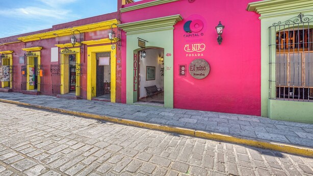 A row of colorful buildings with a prominent pink building labeled "El Nido Posada" and "Capital O". - Capital O El Nito Posada (Oaxaca)