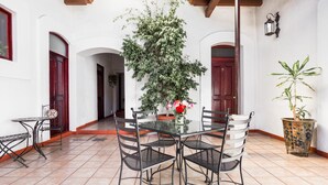 An outdoor patio with a round table and four chairs, surrounded by potted plants and a tiled floor. - Capital O El Nito Posada (Oaxaca)
