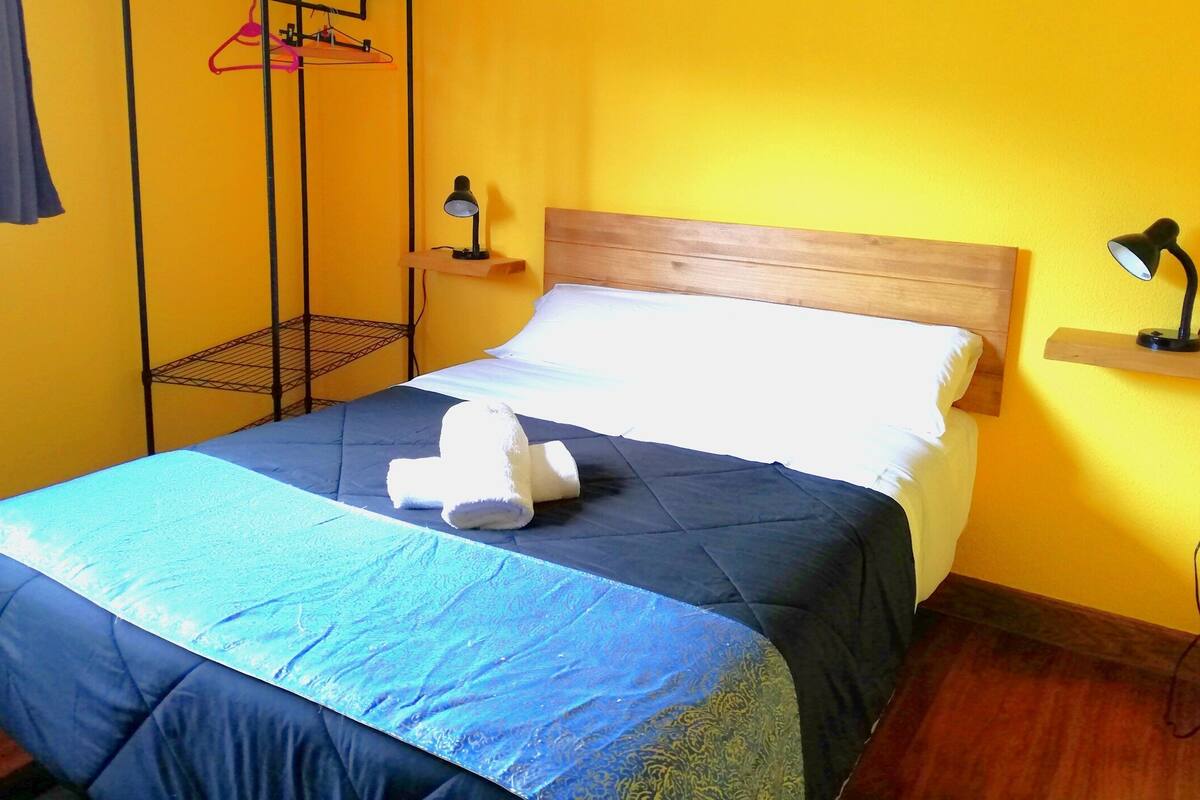 A bed with a blue and white duvet, a wooden headboard, and two bedside lamps.