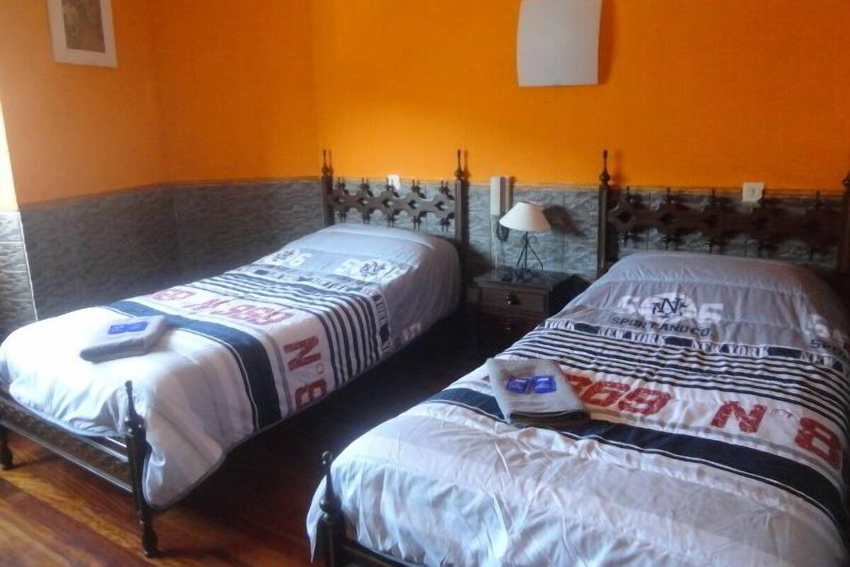 Two single beds in a room with orange walls and a stone accent wall.