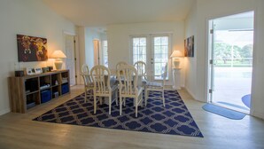 Un comedor con una mesa dispuesta para cuatro, un tapete azul estampado y un mueble de madera con contenedores de almacenamiento.