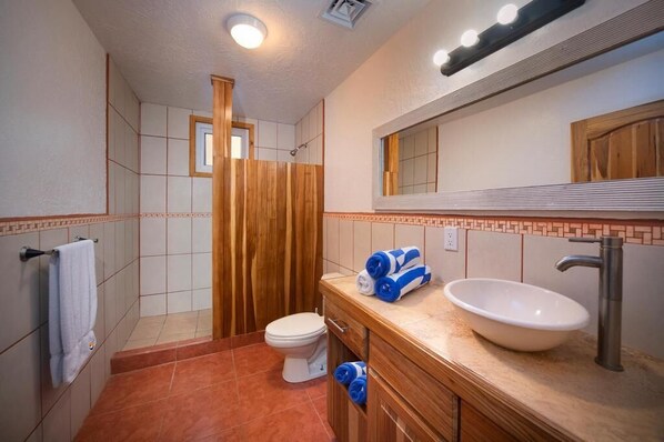 A bathroom with a toilet, sink, and shower area.