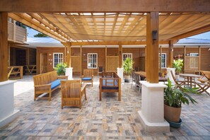 A covered patio area with wooden furniture and potted plants. - Mr. Tucan Hotel (Roatan)