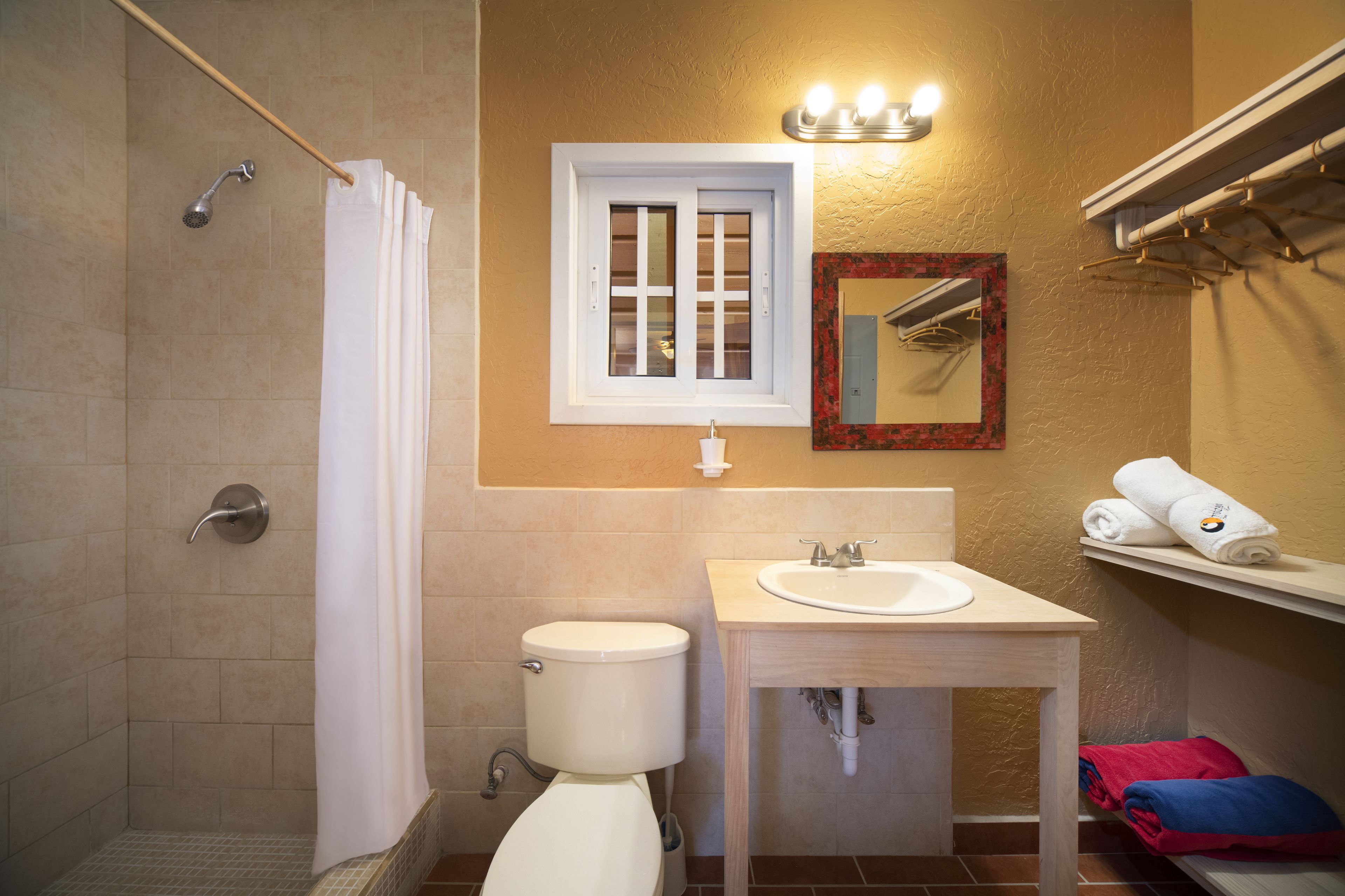A bathroom with a shower, toilet, sink, and towel rack.