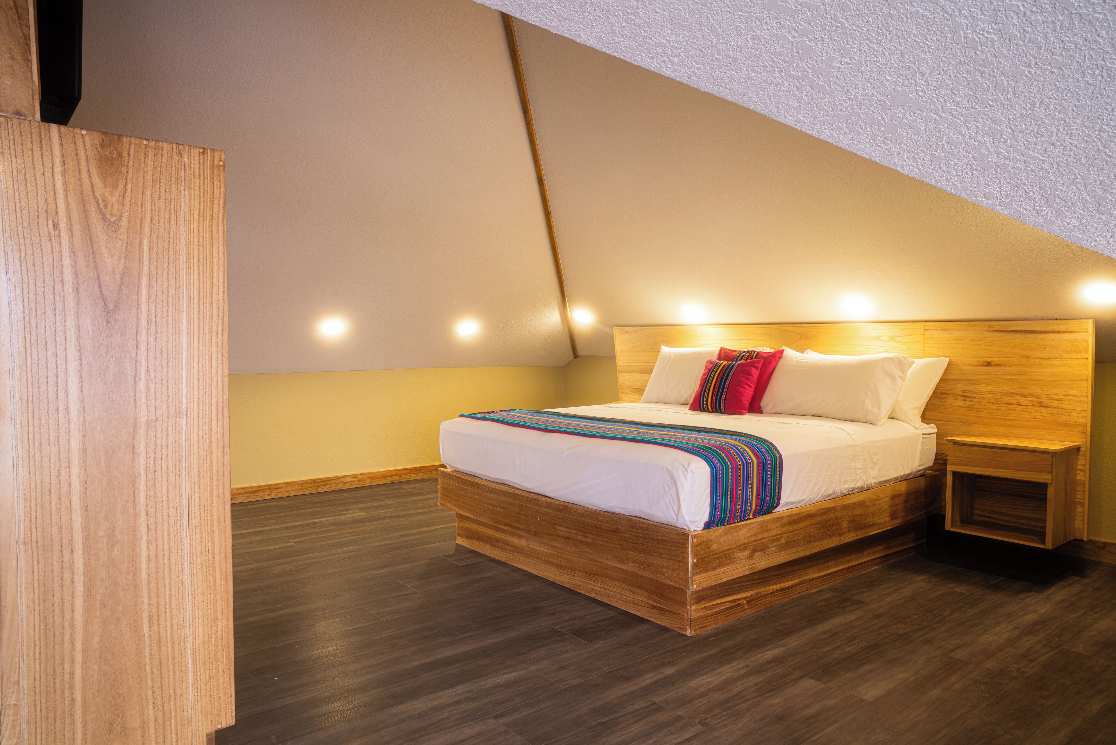 A bedroom with a wooden bed, white bedding, and a nightstand.