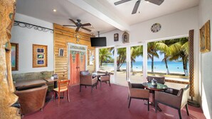 A restaurant with a view of the beach, wooden walls, and ceiling fans.
