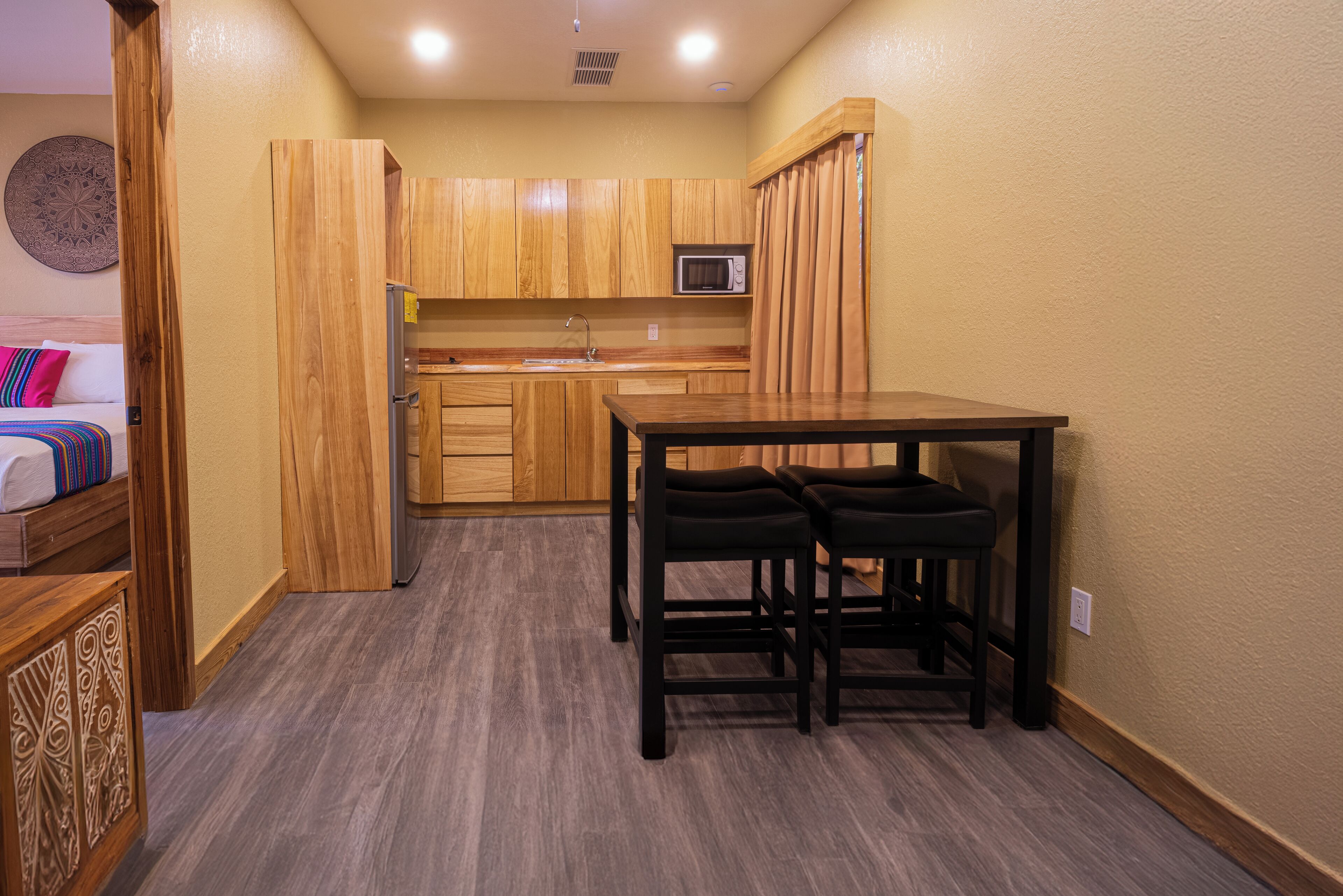 Una cocina compacta con armarios de madera, un microondas y un comedor con dos sillas.