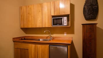Una cocina compacta con armarios de madera, microondas integrado, pileta de acero inoxidable y lavavajillas.
