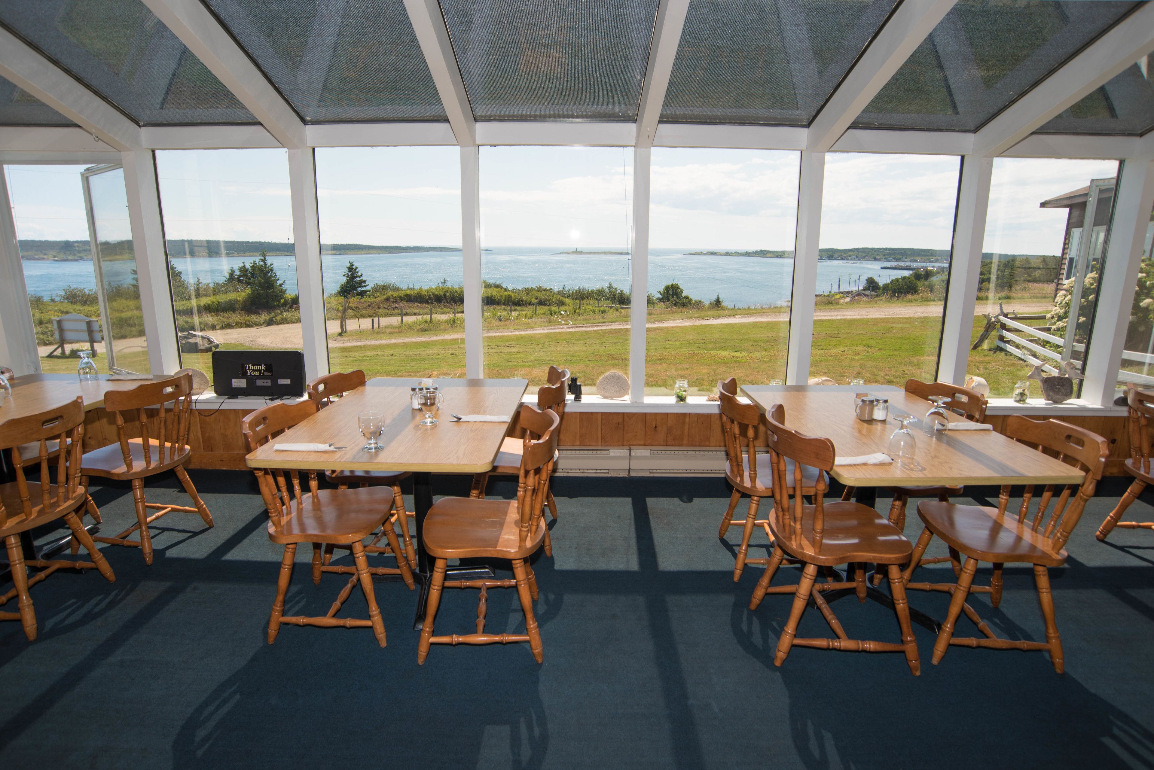 Un restaurant doté de grandes fenêtres offrant une vue panoramique sur un lac et des espaces verdoyants.