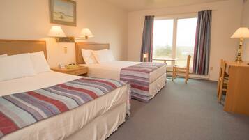 Een hotelkamer met twee bedden, een bureau, een stoel en een raam met gordijnen.