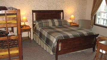 Un dormitorio con una cama de madera, dos lámparas de noche, una silla y un ventanal con cortinas.