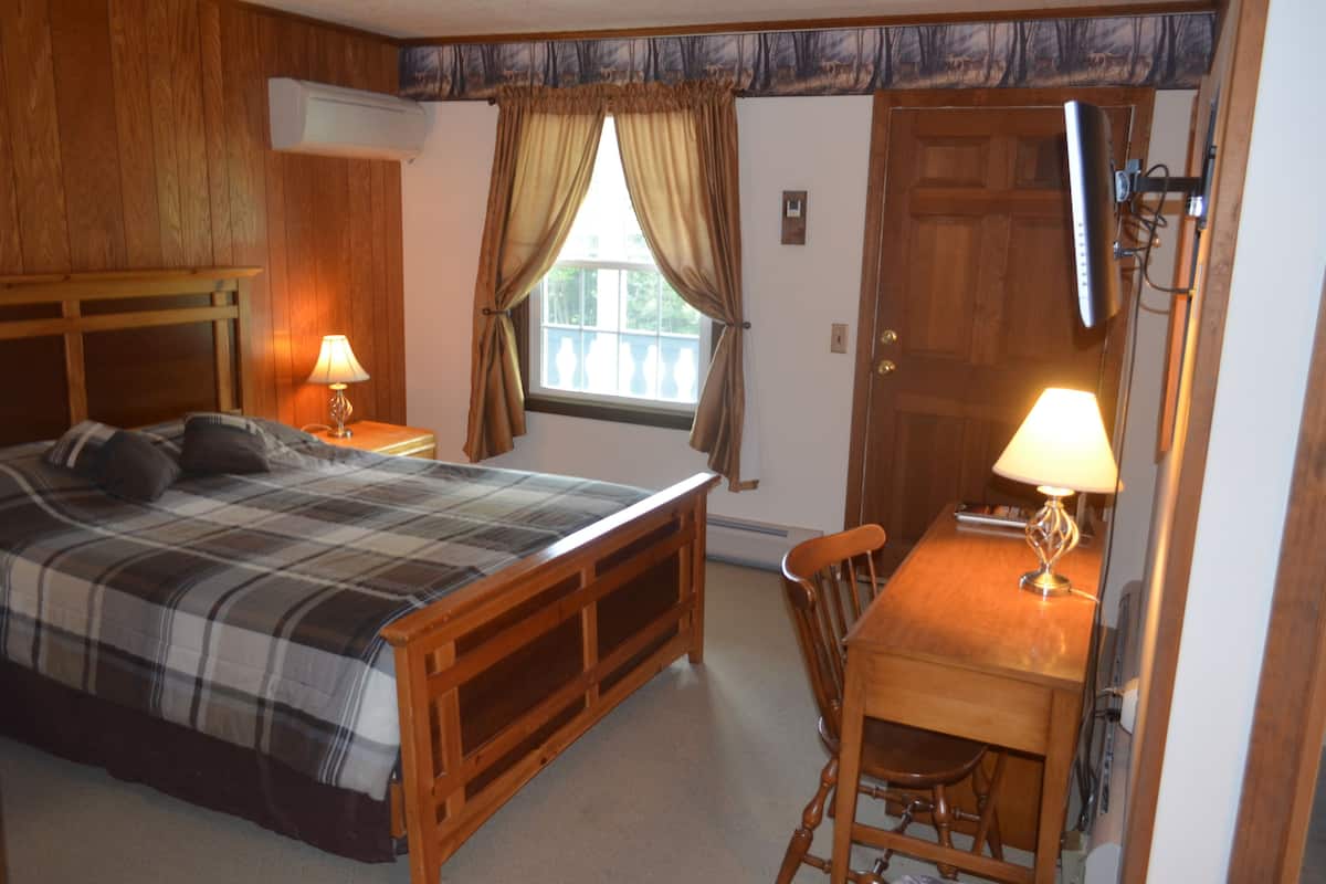 A bedroom with a bed, a desk, and a chair.