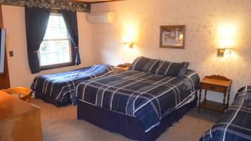 A room with two beds, a wooden desk, a chair, and a window with curtains.