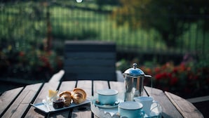 A wooden table with a tray of croissants, a coffee pot, and cups and saucers.
