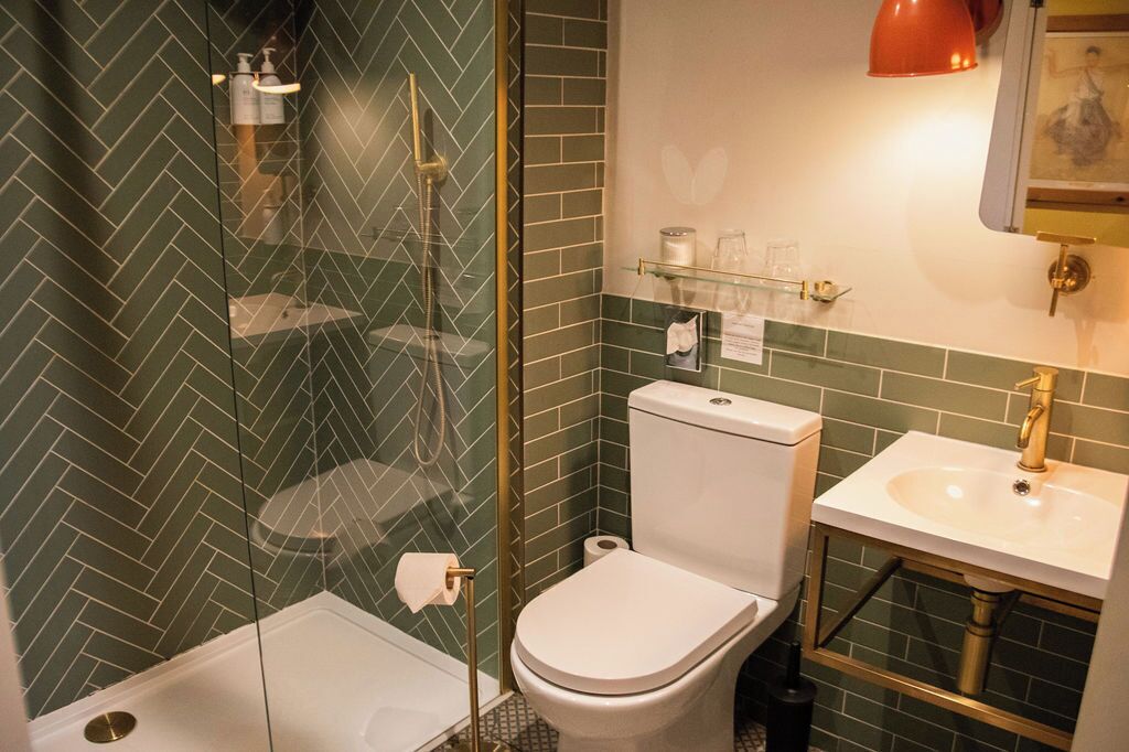 Une salle de bain avec une douche à parois de verre, des toilettes blanches et un lavabo avec un robinet doré.