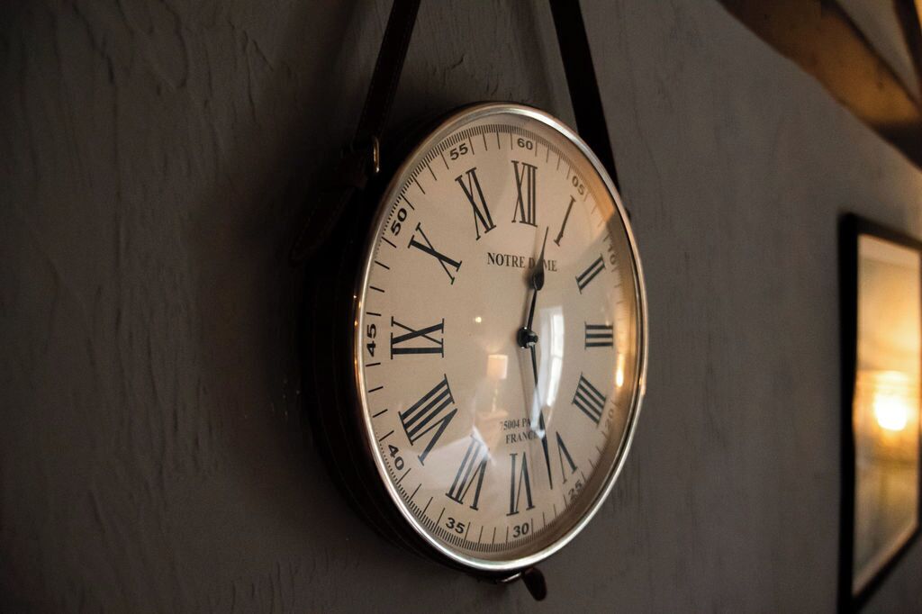 A wall-mounted clock with Roman numerals and the inscription 'NOTRE DAME' and 'FRANCE'.