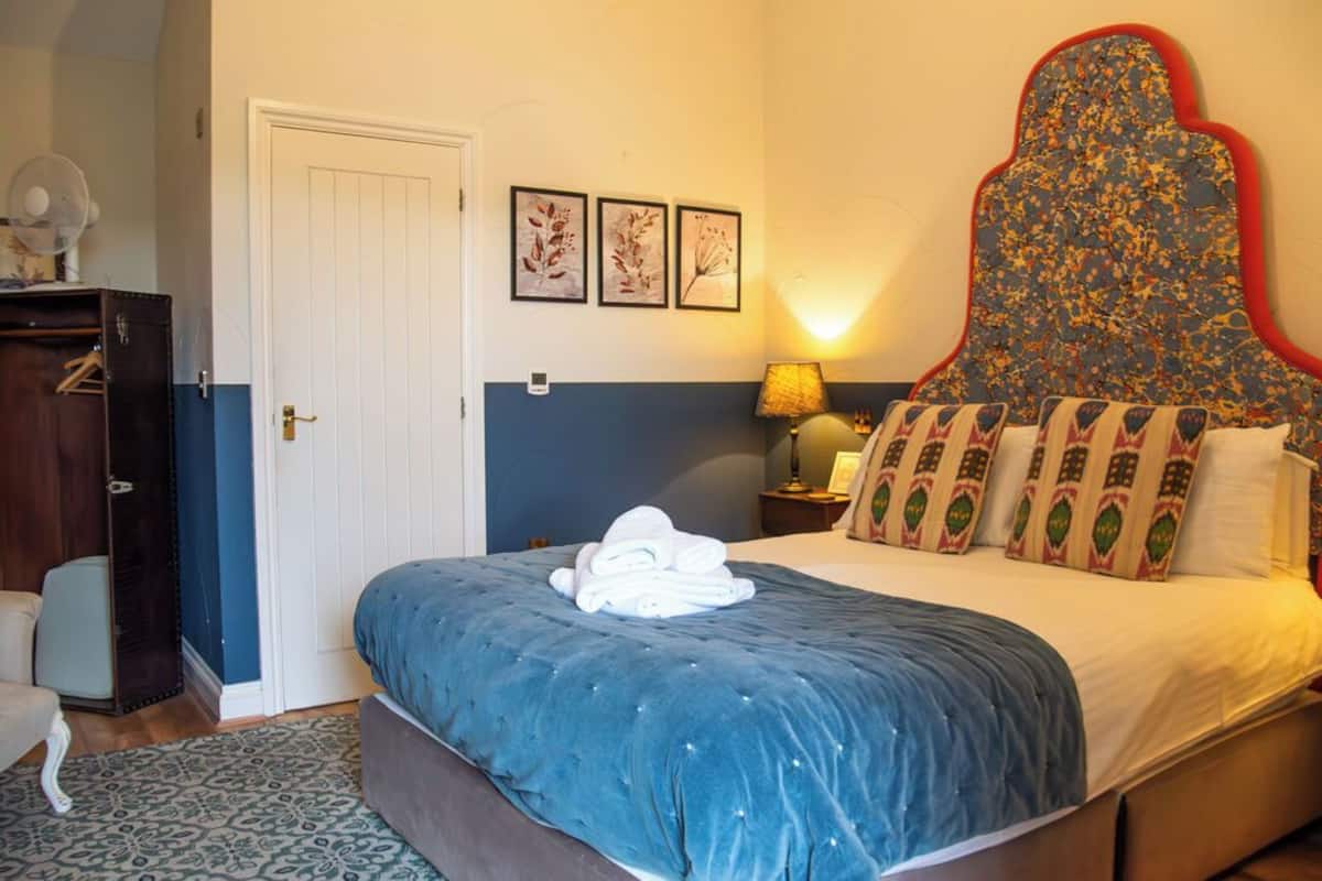 A bedroom with a bed, a dresser, a door, and wall art.