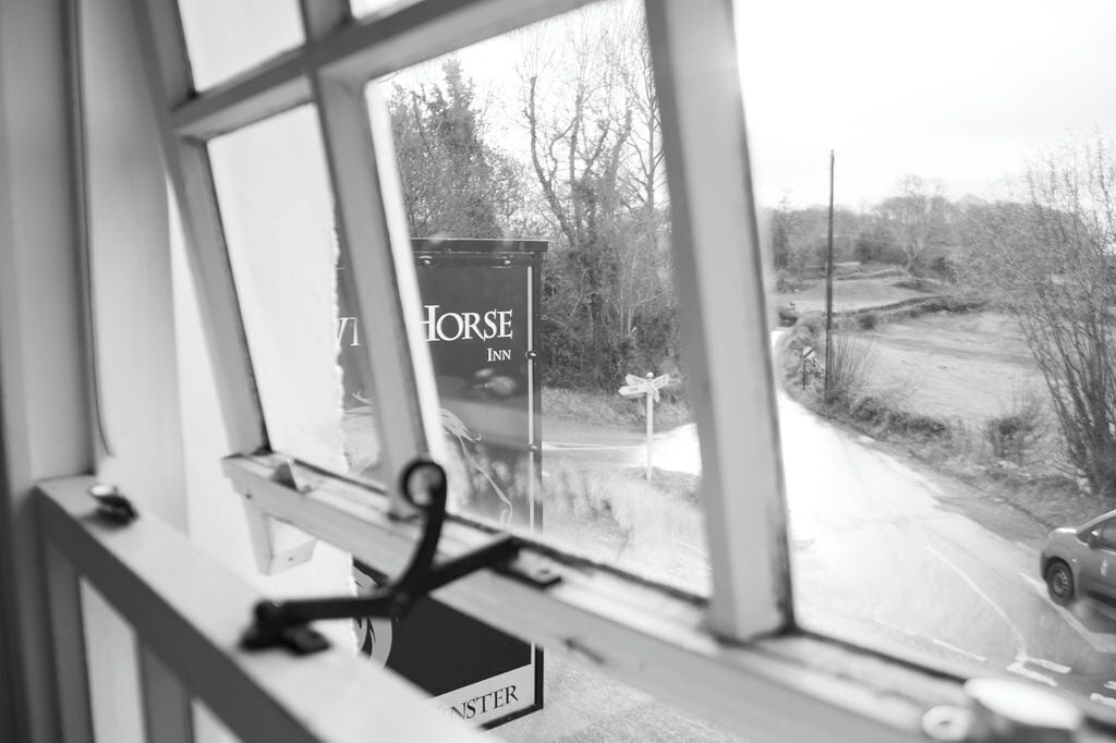 A window view of a sign for 'Horse Inn' with a rural landscape visible outside.