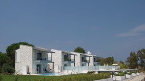 A modern two-story house with a stone facade, a swimming pool, and outdoor seating.