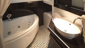 Un baño moderno con una bañera independiente, un tocador con espejo y un suelo estampado.