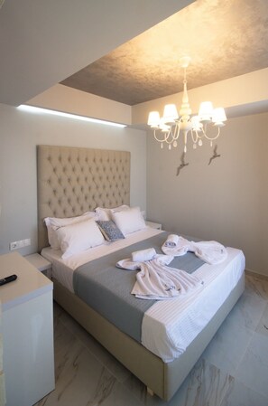 A bedroom with a tufted headboard, a bed with white linens, a bedside table, and a chandelier.