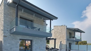 Una casa moderna de dos pisos con piscina, fachada de piedra y zona de estar al aire libre.
